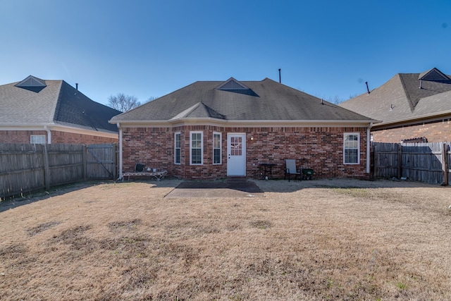 rear view of house featuring brick siding, a yard, and a fenced backyard