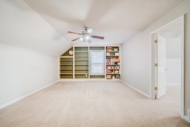 interior space with carpet, built in shelves, baseboards, and a textured ceiling