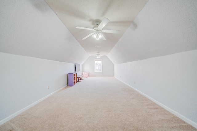 additional living space featuring carpet floors, vaulted ceiling, a textured ceiling, ceiling fan, and baseboards