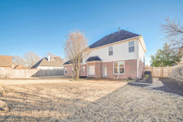 back of property featuring brick siding, fence, and a lawn