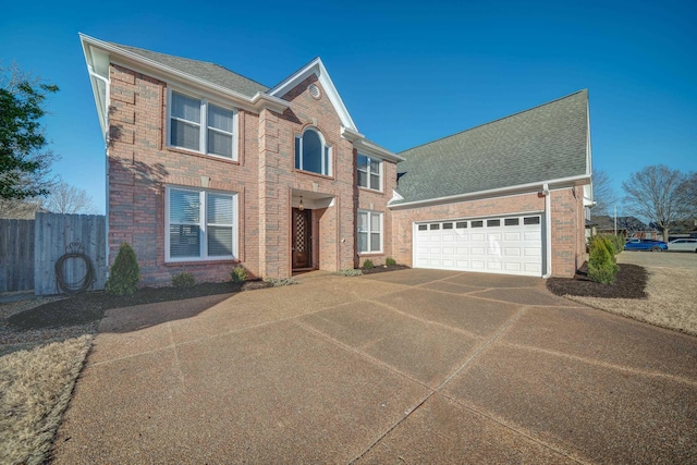 traditional-style house with a garage, concrete driveway, brick siding, and fence