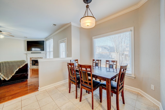 dining area with light tile patterned flooring, a fireplace, visible vents, and crown molding