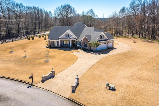 view of front of property featuring concrete driveway, roof with shingles, a wooded view, and an attached garage