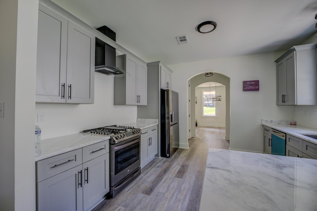 kitchen featuring light stone counters, arched walkways, fridge with ice dispenser, gas range, and dishwasher