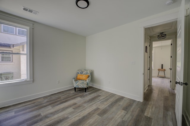 unfurnished room featuring baseboards, wood finished floors, visible vents, and attic access