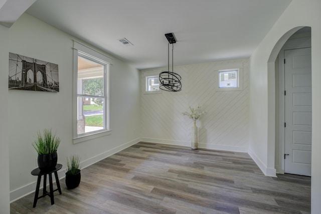 unfurnished dining area featuring a healthy amount of sunlight, visible vents, baseboards, and wood finished floors