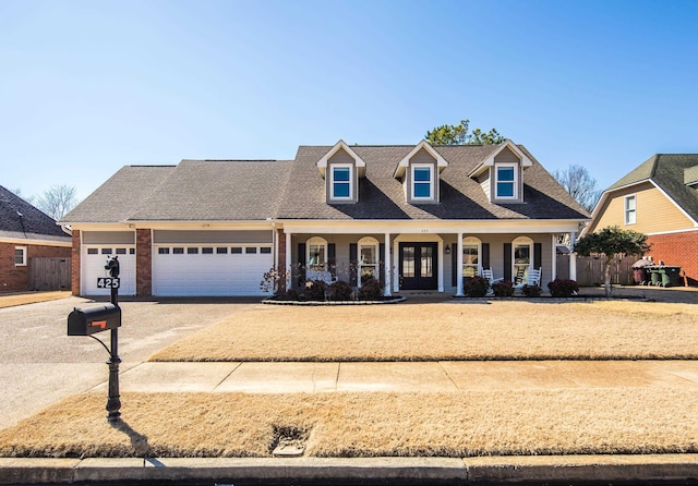 view of front of house with a garage, covered porch, concrete driveway, and roof with shingles