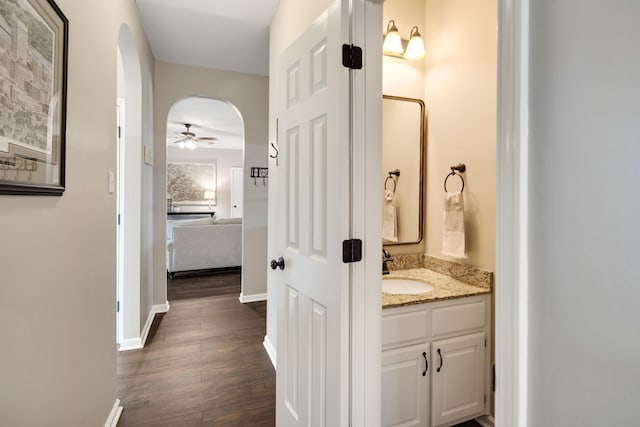 bathroom featuring ceiling fan, vanity, baseboards, and wood finished floors