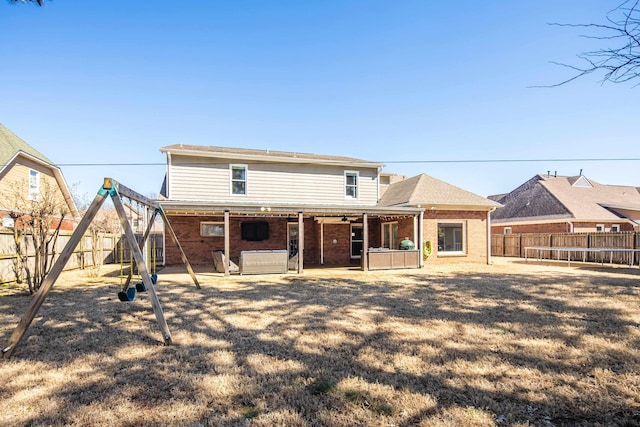 rear view of house featuring a trampoline, a fenced backyard, brick siding, and a patio