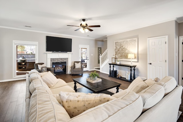 living area featuring ornamental molding, a fireplace, dark wood finished floors, and visible vents