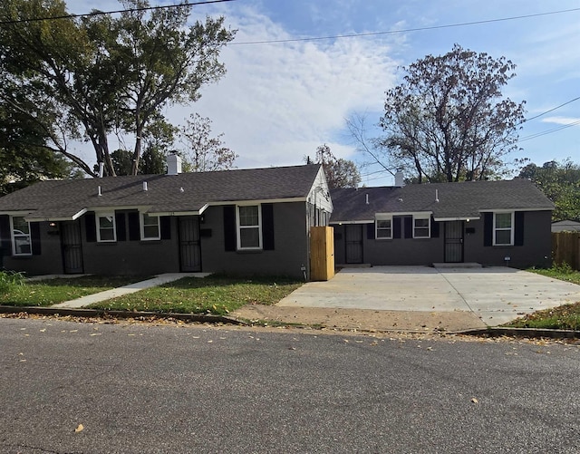 ranch-style house featuring driveway, brick siding, fence, and a chimney