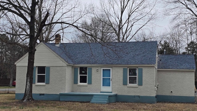 view of front of home featuring crawl space, roof with shingles, a chimney, and brick siding