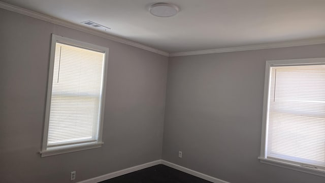 unfurnished room with ornamental molding, a wealth of natural light, visible vents, and baseboards