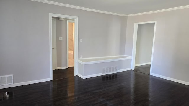 empty room with baseboards, visible vents, dark wood finished floors, and ornamental molding