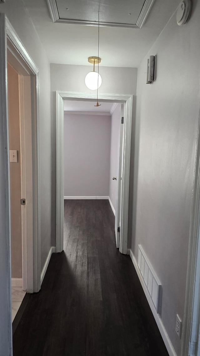 hallway with attic access, visible vents, baseboards, and wood finished floors