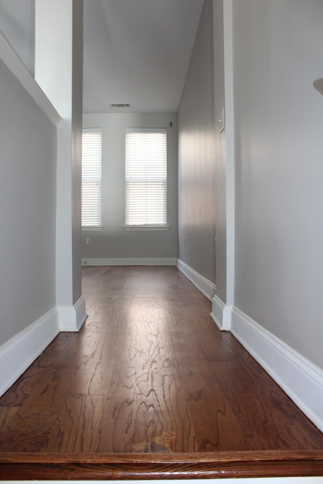 spare room with visible vents, baseboards, and wood finished floors