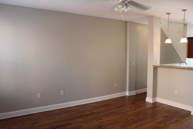 unfurnished room with dark wood-type flooring, ceiling fan, and baseboards