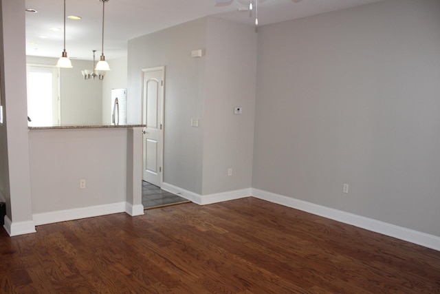 interior space with baseboards, wood finished floors, and ceiling fan with notable chandelier