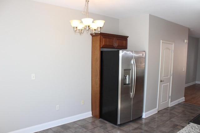 kitchen with baseboards, pendant lighting, stainless steel fridge, and an inviting chandelier