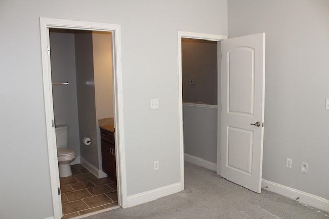 unfurnished bedroom with carpet, connected bathroom, and baseboards