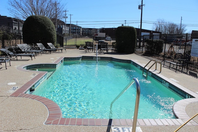 community pool with a patio and fence