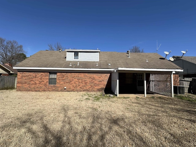 rear view of house featuring brick siding and fence