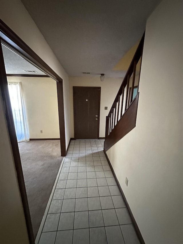 hallway featuring light carpet, light tile patterned flooring, stairway, and baseboards