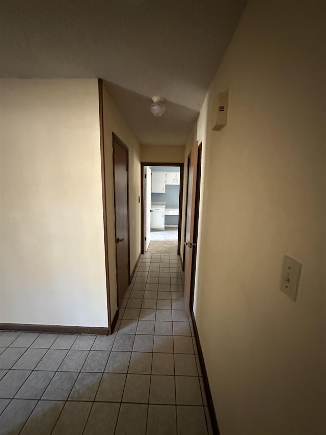 hallway featuring light tile patterned flooring and baseboards