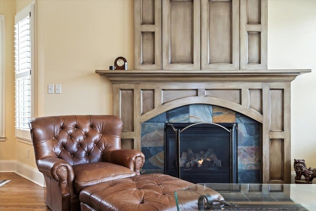 sitting room featuring a fireplace, baseboards, and wood finished floors