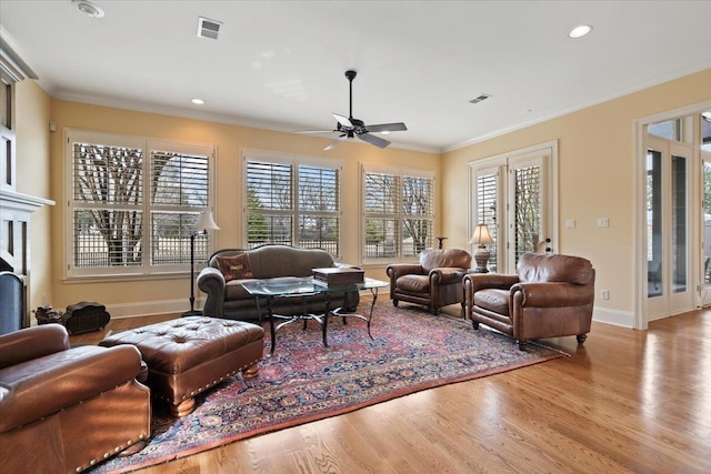 living area featuring ornamental molding, visible vents, baseboards, and wood finished floors