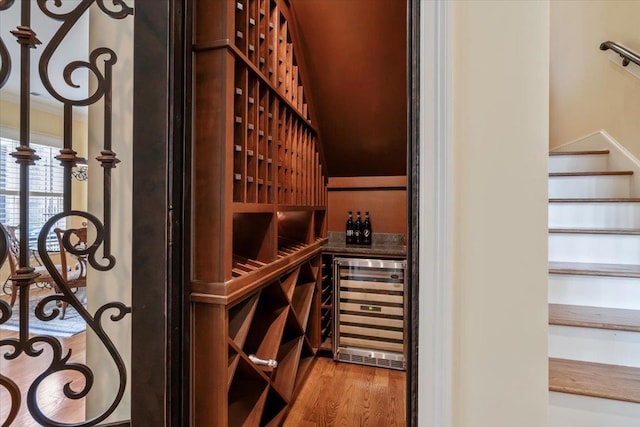 wine area featuring wine cooler, crown molding, and wood finished floors