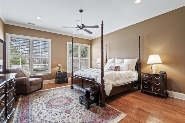 bedroom featuring ornamental molding, wood finished floors, visible vents, and baseboards