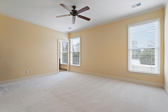 empty room with light carpet, a healthy amount of sunlight, visible vents, and crown molding