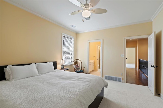 bedroom featuring ceiling fan, ornamental molding, ensuite bath, and visible vents