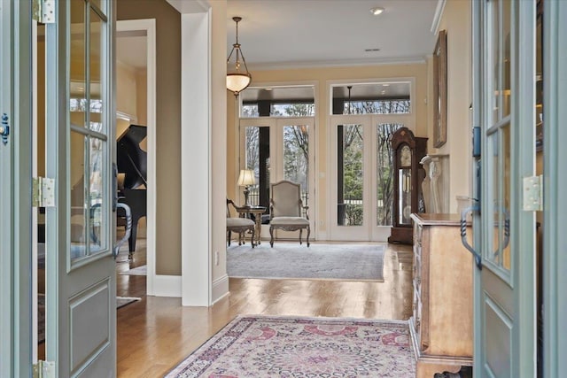 foyer entrance with baseboards, ornamental molding, wood finished floors, and french doors