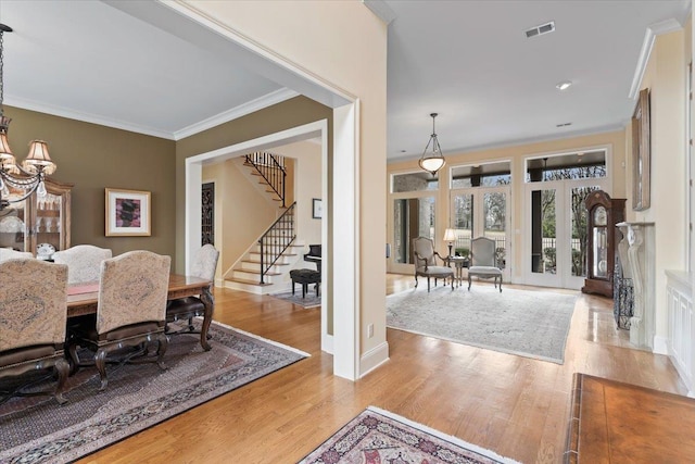 dining area featuring wood finished floors, visible vents, baseboards, stairway, and crown molding