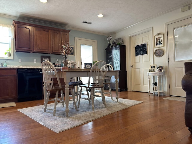 dining room with a textured ceiling, hardwood / wood-style flooring, recessed lighting, visible vents, and crown molding