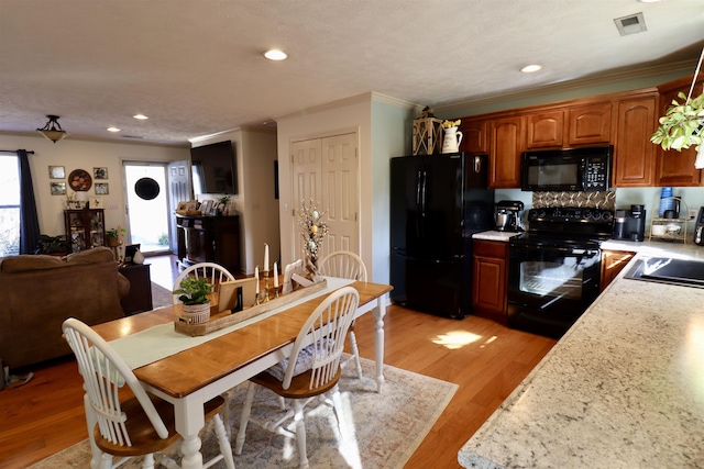 kitchen with light wood-type flooring, light countertops, a sink, and black appliances