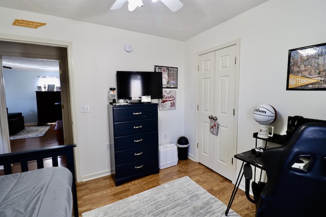 bedroom with light wood-type flooring, a closet, baseboards, and a ceiling fan