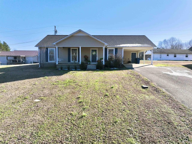 view of front facade featuring a porch, a shingled roof, driveway, a carport, and a front lawn