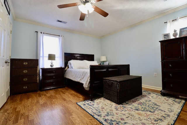 bedroom with visible vents, baseboards, a ceiling fan, crown molding, and light wood-style floors