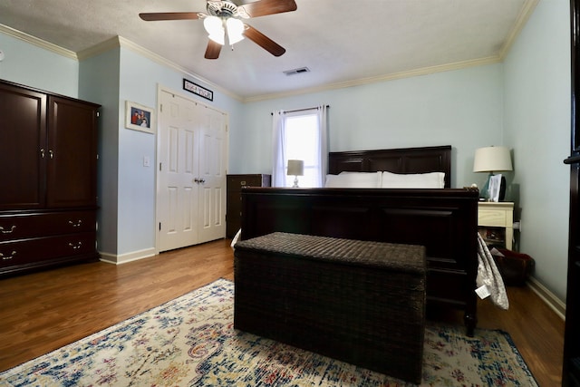 bedroom featuring baseboards, visible vents, ceiling fan, ornamental molding, and wood finished floors