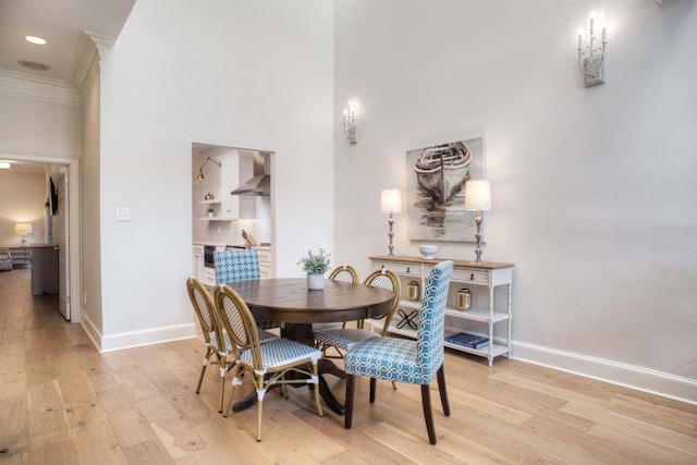 dining room with light wood-style floors, baseboards, and ornamental molding