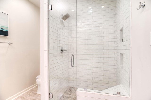 full bath with toilet, a shower stall, and baseboards