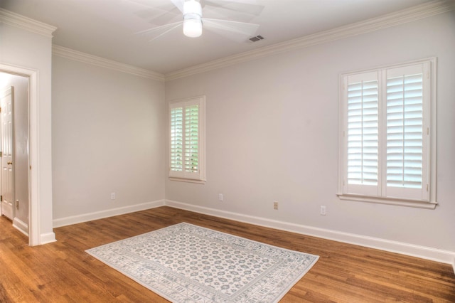 empty room with baseboards, visible vents, a ceiling fan, ornamental molding, and wood finished floors