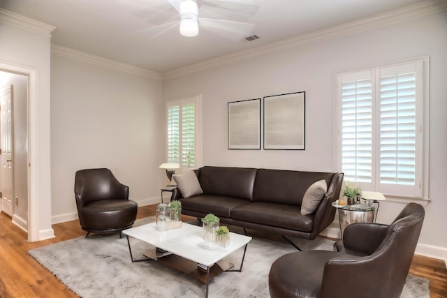 living area with a ceiling fan, visible vents, baseboards, and wood finished floors