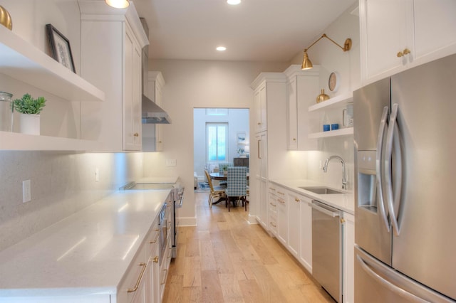 kitchen featuring appliances with stainless steel finishes, open shelves, a sink, and light countertops