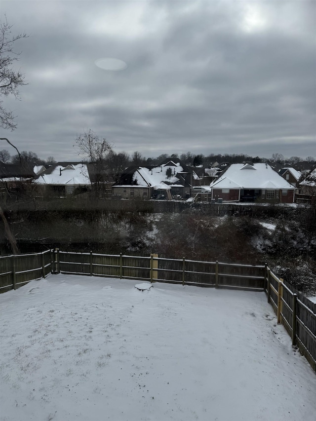 snowy yard featuring a residential view and a fenced backyard