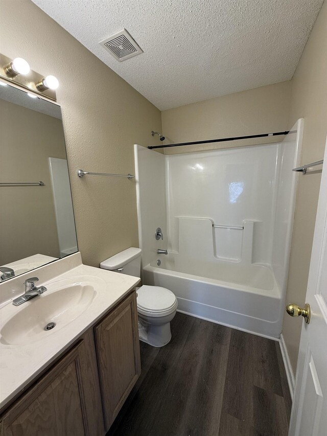 bathroom with visible vents, toilet, vanity, a textured ceiling, and wood finished floors