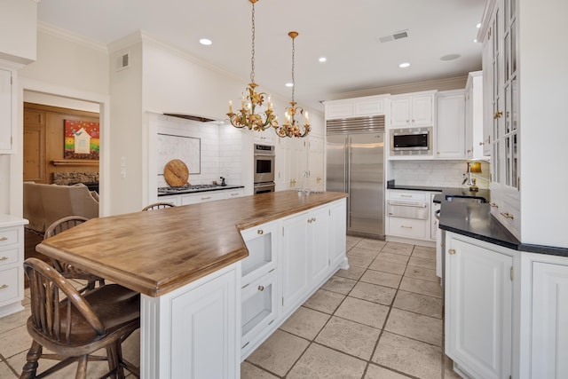 kitchen featuring a center island, visible vents, white cabinets, wood counters, and built in appliances